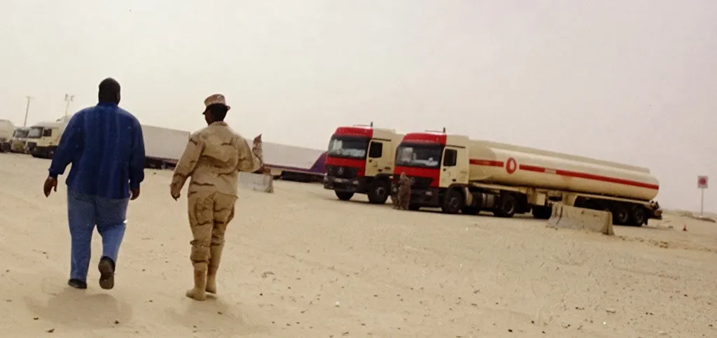 Personnel walking toward tanker trucks in a desert logistics yard